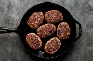 Salisbury steaks sizzling in a pan, developing a perfectly browned crust as they cook to golden, juicy perfection.