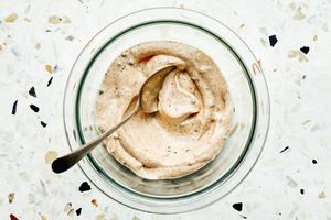 old bay seasoning mayonnaise in a glass bowl with a spoon. made with mayonnaise, chives, Old Bay Seasoning and Lemon juice.