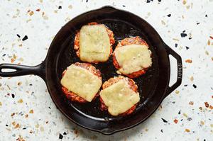 homemade salmon burger patties topped with slices of dill havarti cheese being fried in a skillet