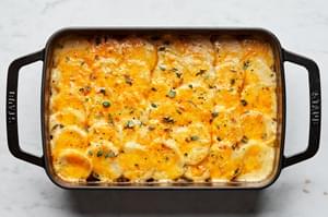 homemade scalloped potatoes in a casserole dish made with milk, cheese, thyme, and nutmeg
