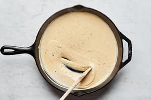 sauce for scalloped potatoes in a skillet made with cheese, milk, butter, flour, spices and cheese