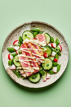 seared ahi tuna served on top of cucumber salad drizzled with  wasabi mayo and sprinkled with sesame seeds