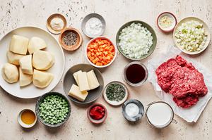 potatoes, ground beef, chopped vegetables, milk, olive oil, spices and other ingredients in bowls to make shepherd's pie