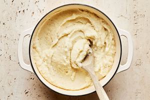 mashed potatoes being stirred in a pot made with milk, butter, garlic powder, salt and pepper