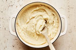 mashed potatoes being stirred in a pot made with milk, butter, garlic powder, salt and pepper