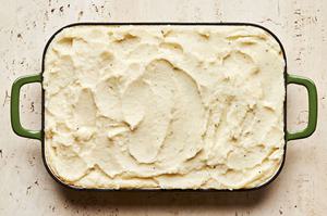 a shepherd's pie made with a beef and vegetable mixture topped with mashed potatoes ready to be baked in the oven
