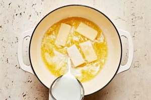 milk being poured into a pot with butter