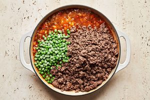 a savory filling for shepherd's pie being cooked in a skillet with beef, peas, vegetables, tomato paste and spices
