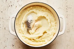 garlic powder, salt and pepper added to mashed potatoes in a pot