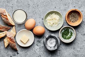butter, eggs, heavy cream, salt, pepper, parmesan, chives and crusty bread in bowls to make shirred eggs