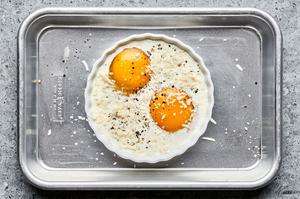 2 eggs and heavy cream in a greased ramekin seasoned with salt and pepper and sprinkled with parmesan on a baking sheet