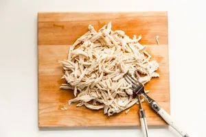 a plate filled with shredded chicken breast on a striped linen