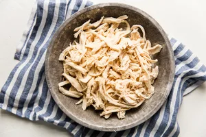 homemade shredded chicken in a bowl sitting on top of a cloth towel