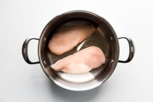 2 raw chicken breasts in a pot with salt and covered with water ready to be boiled to make shredded chicken