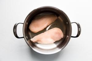 2 raw chicken breasts in a pot with salt and covered with water ready to be boiled to make shredded chicken