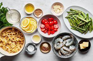 ingredients for shrimp scampi en papillote including shrimp, asparagus, cherry tomatoes, spices, chicken stock and noodles