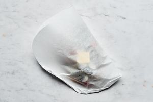 parchment paper being folded around the shrimp scampi to make created an envelope for the shrimp scampi to bake