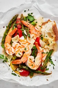 Shrimp Scampi En Papillote (in parchment) made with shrimp, asparagus, cherry tomatoes, spices and sprinkled with parsley