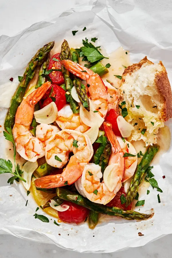 Shrimp Scampi En Papillote (in parchment) made with shrimp, asparagus, cherry tomatoes, spices and sprinkled with parsley