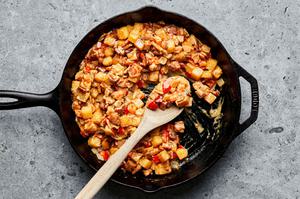 bacon, potatoes, onion, bell pepper, cream, worcestershire sauce, paprika, salt and pepper being cooked together in a skillet