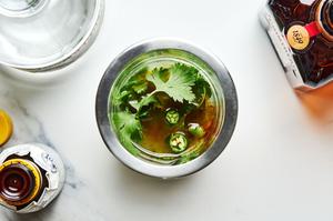 muddled serrano pepper and lime juice in a cocktail shaker with tequila, triple sec, cilantro and bitters