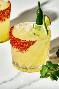 A spicy margarita with juicy lime, tequila, a hint of serrano Chile with a Tajin seasoning rim and a lime and Serrano garnish