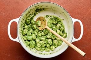 gnocchi being tossed in spinach pesto in a pot