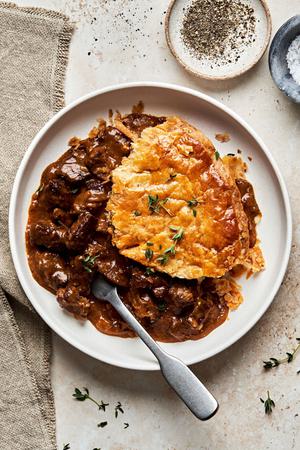 a slice of steak pie on a plate with a fork