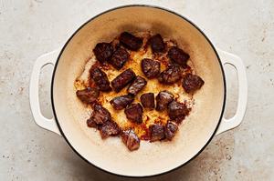 stew beef seasoned with salt being cooked in a dutch oven with vegetable oil until browned