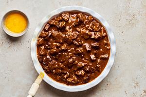 steak pie filling in a pie pan ready to be topped with puff pastry