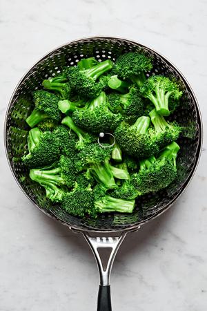 broccoli being steamed in a pot of salted water with a steamer basket set inside