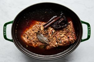 corned beef in a dutch oven made with seasoning, beef stock, water, cinnamon stick, bay leaves, chili, garlic and beer