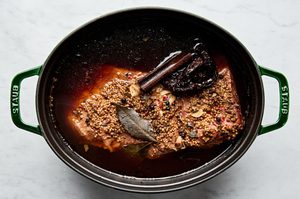 corned beef in a dutch oven made with seasoning, beef stock, water, cinnamon stick, bay leaves, chili, garlic and beer