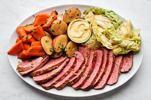 sliced Corned beef and cabbage, with potatoes, carrots and mustard on a large serving platter, an Irish comfort food meal
