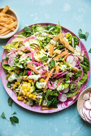 Homemade Tex-Mex salad with creamy oregano dressing topped with Monterey Jack cheese and crispy tortilla strips on a plate