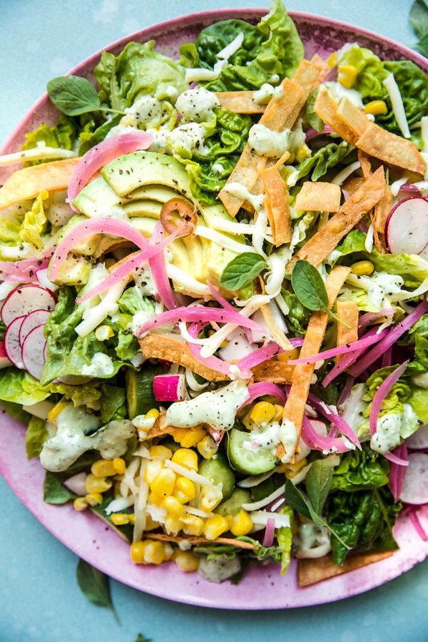 Homemade Tex-Mex salad with creamy oregano dressing topped with Monterey Jack cheese and crispy tortilla strips on a plate