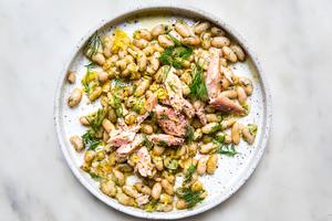 white plate topped white beans and oil topped with dill and smoked trout