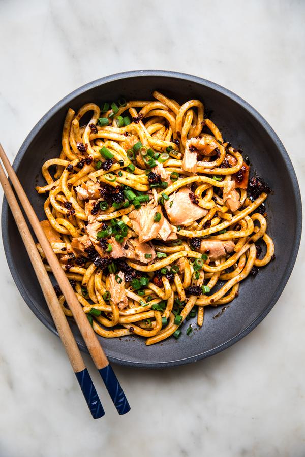 Bowl filled with udon noodles topped with green onions, smoked salmon and chili crisp