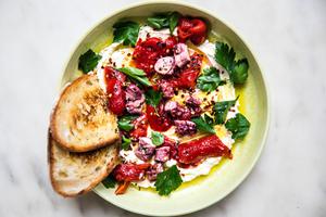 Bowl of whipped feta topped with roasted red peppers, tinned octopus and parsley with toasted bread alongside.