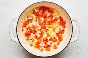 carrots and onion being cooked in butter in a pot to make tomato Soup