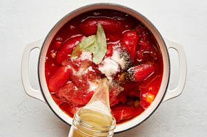 butter, carrots, onions, tomatoes, bay leaves, olive oil, salt, pepper and chicken stock being boiled in a pot for Soup