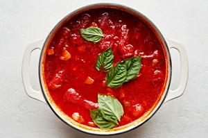 butter, carrots, onions, tomatoes, olive oil, salt, pepper, chicken stock and basil leaves in a pot for Soup