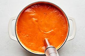 homemade tomato Soup being blended in a pot with an immersion blender