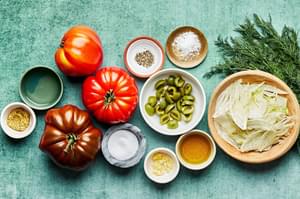 tomatoes, fennel, olives, vinegar, garlic, dill, olive oil, stone ground mustard, salt & pepper in bowls on the counter