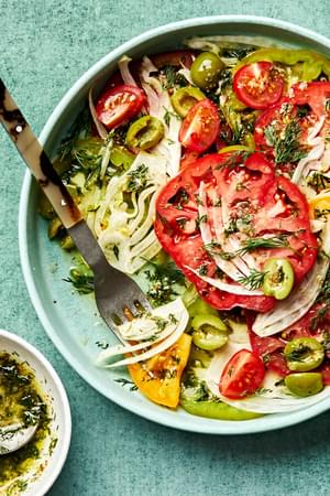 the Best Tomato Salad in a bowl with a fork made with tomatoes, fennel, olives and fresh dill