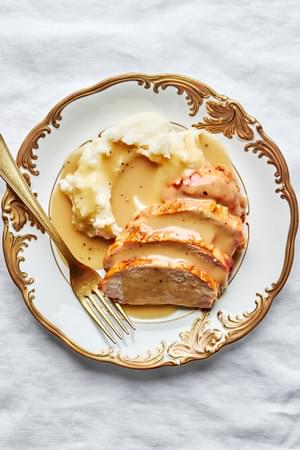 homemade turkey gravy seasoned with thyme, bay leaf and parsley on top of  turkey and mashed potatoes