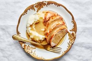 homemade turkey gravy seasoned with thyme, bay leaf and parsley on top of  turkey and mashed potatoes