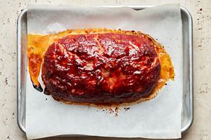 homemade turkey meatloaf coated in a brown sugar sauce just out of the oven cooling on a parchment lined baking sheet