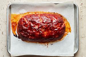 homemade turkey meatloaf coated in a brown sugar sauce just out of the oven cooling on a parchment lined baking sheet