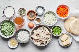 chopped vegetables, turkey stock, shredded turkey, butter, flour, butter, pie crust and spices in bowls for turkey pot pie